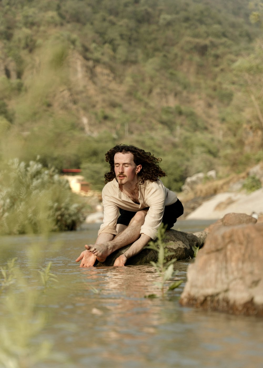 Ein Mann, der auf einem Felsen in einem Fluss sitzt