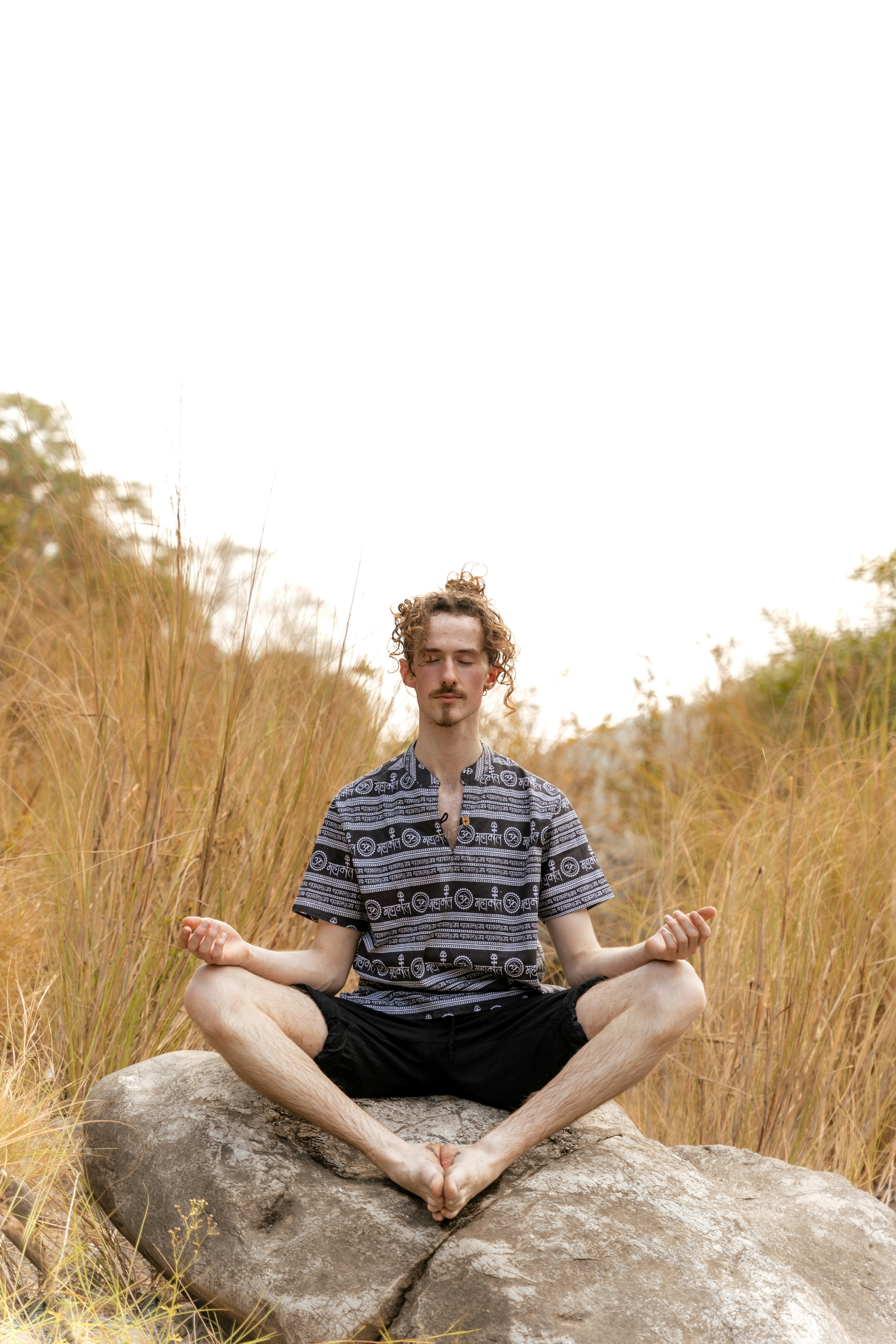 a man sitting on top of a rock in a field