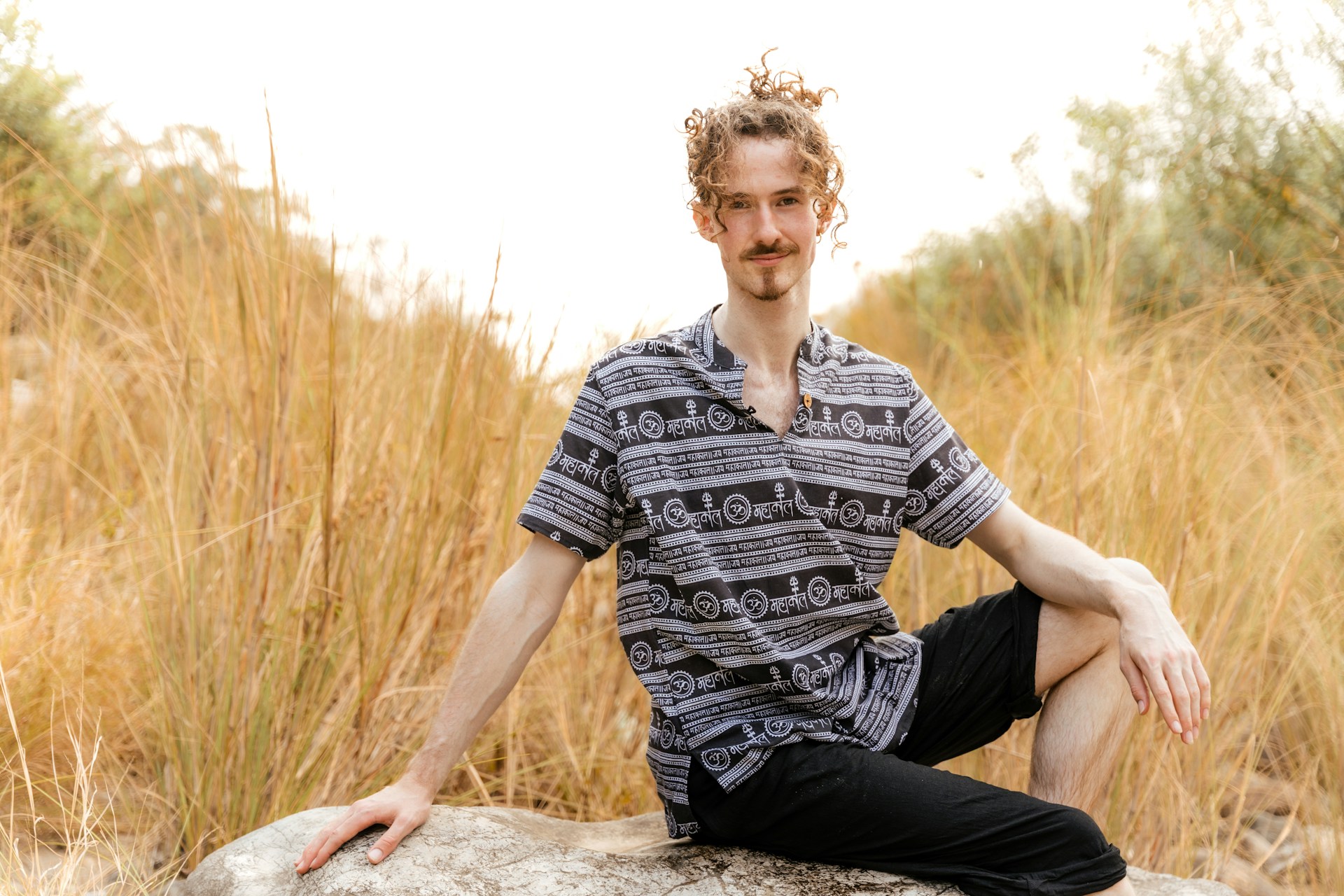 a man sitting on a rock in a field