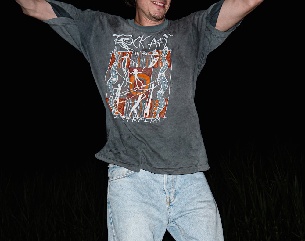 a man in a gray shirt is holding his arms up