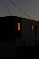Evening shot of a modern house with warm interior lighting visible through large windows.