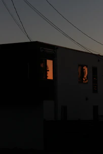 A twilight exterior shot of a modern home with warm interior lights glowing.