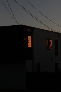 A stunning twilight exterior shot of a modern luxury home with warm interior lights glowing against a deep charcoal sky.
