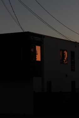 A sleek home with solar panels and a modern battery unit glowing softly under a twilight sky.