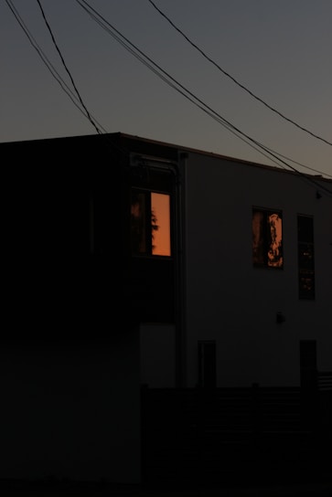 A sleek home with solar panels and a modern battery unit glowing softly under a twilight sky.