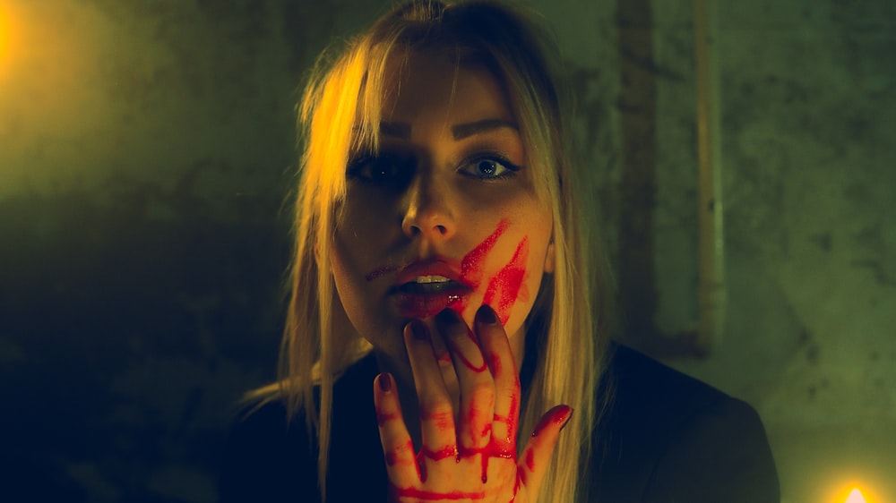 Una mujer con pintura roja en la cara y las manos