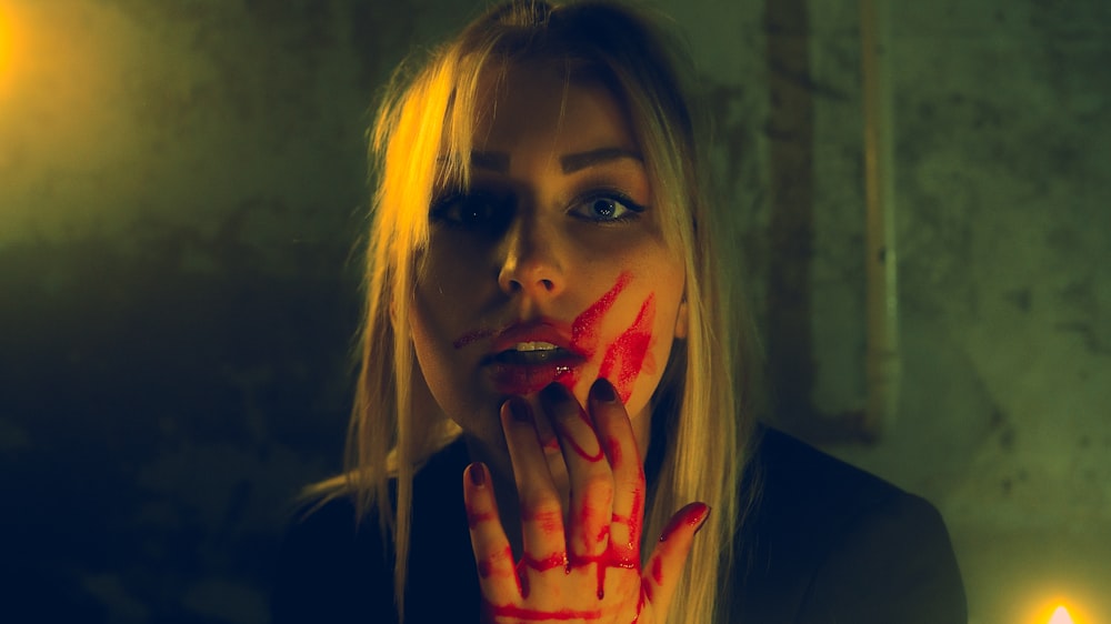 a woman with red paint on her face and hands