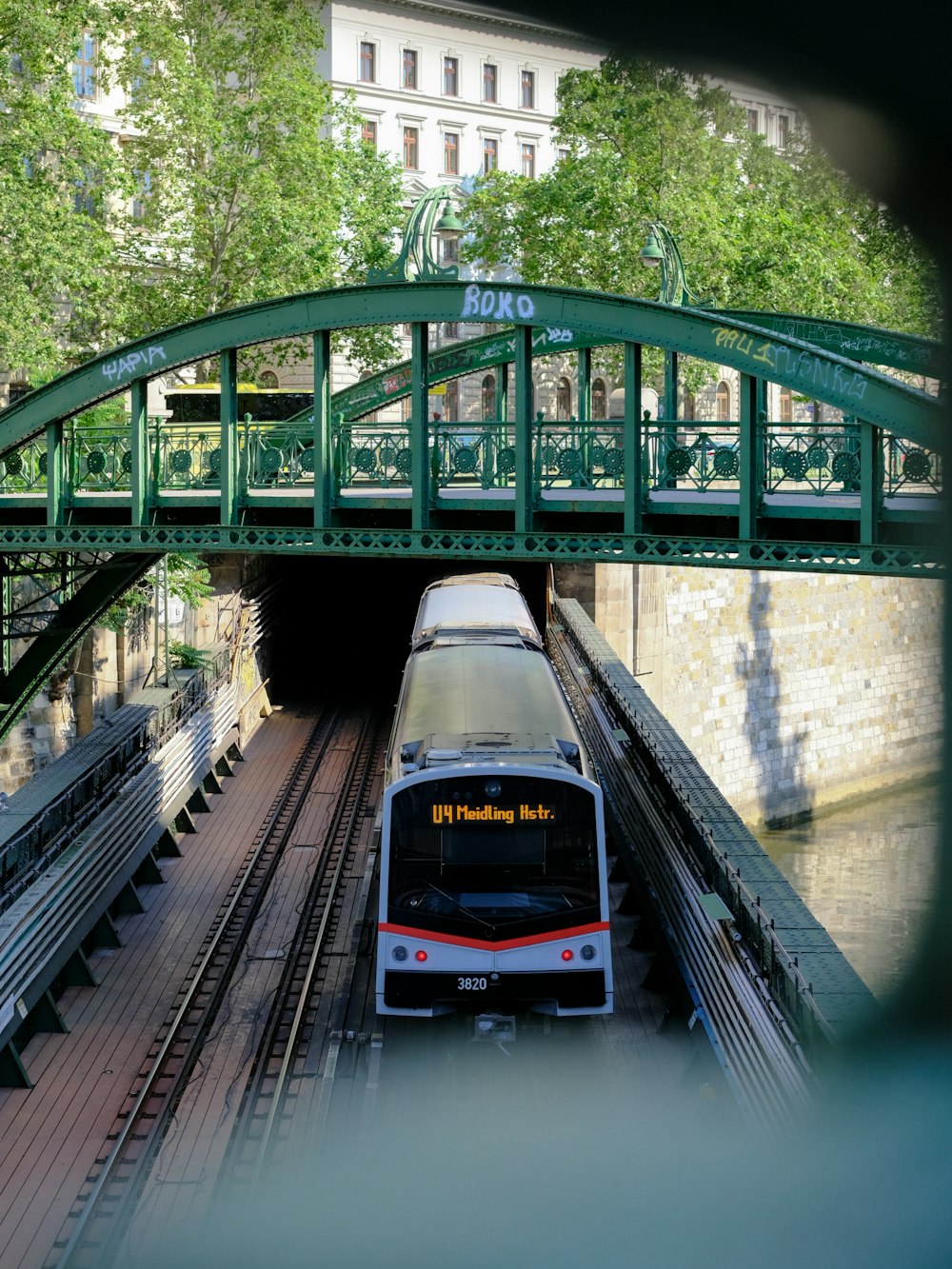 a train traveling under a green bridge over a river