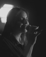 Black and white photo of just esmond singing into a vintage microphone during a recording session.