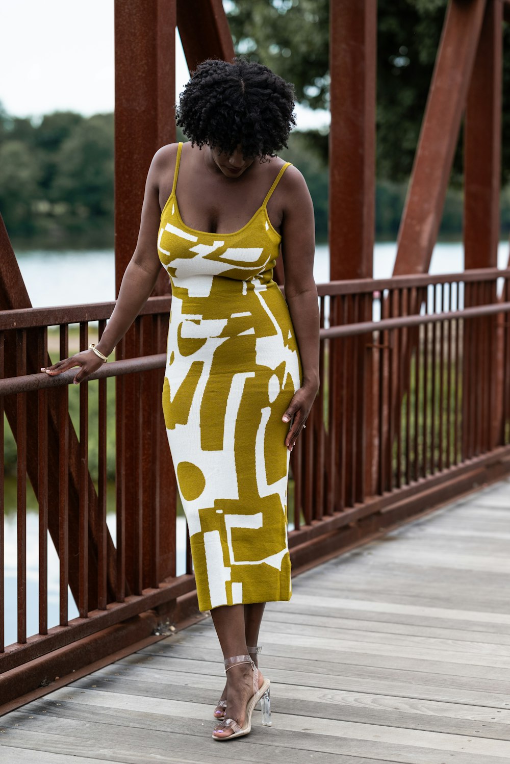 a woman standing on a bridge wearing a yellow and white dress
