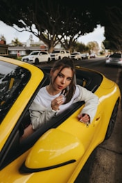 a woman sitting in a yellow sports car