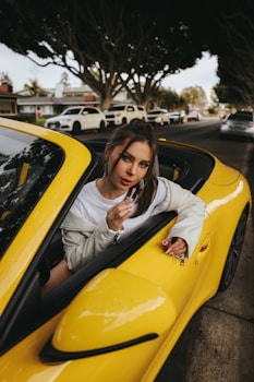 a woman sitting in a yellow sports car