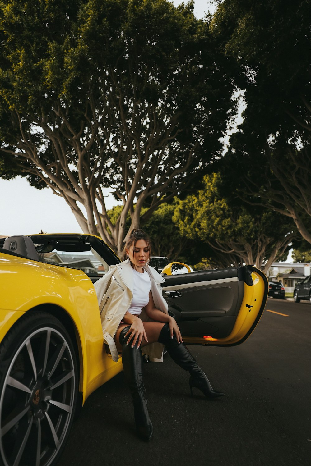 a woman sitting on the back of a yellow sports car