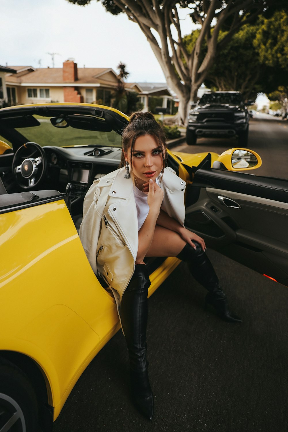 a woman sitting on the hood of a yellow sports car