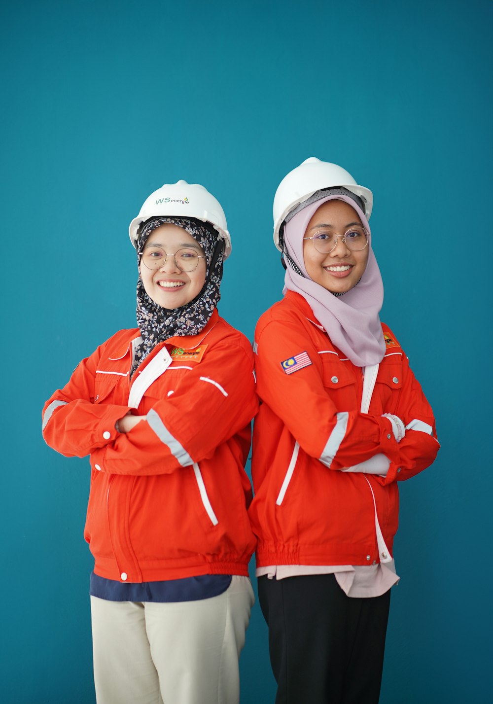 two women standing next to each other in front of a blue background
