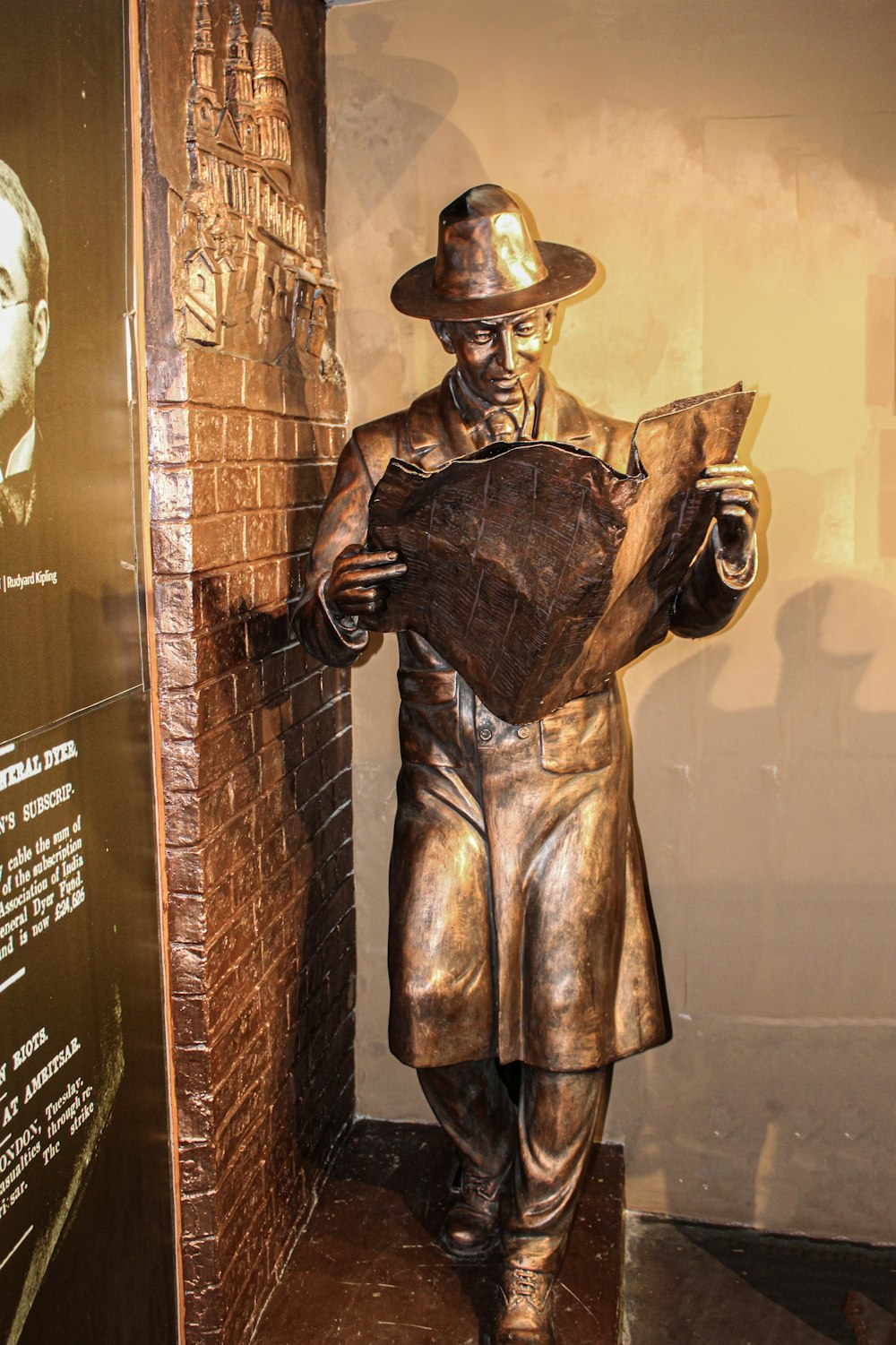 a bronze statue of a man reading a newspaper