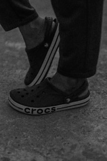 A pair of colorful, personalized Crocs displayed on a rustic wooden surface.