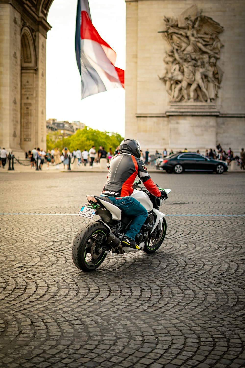 a man riding a motorcycle down a cobblestone street
