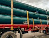 a large truck with a bunch of green pipes on the back of it