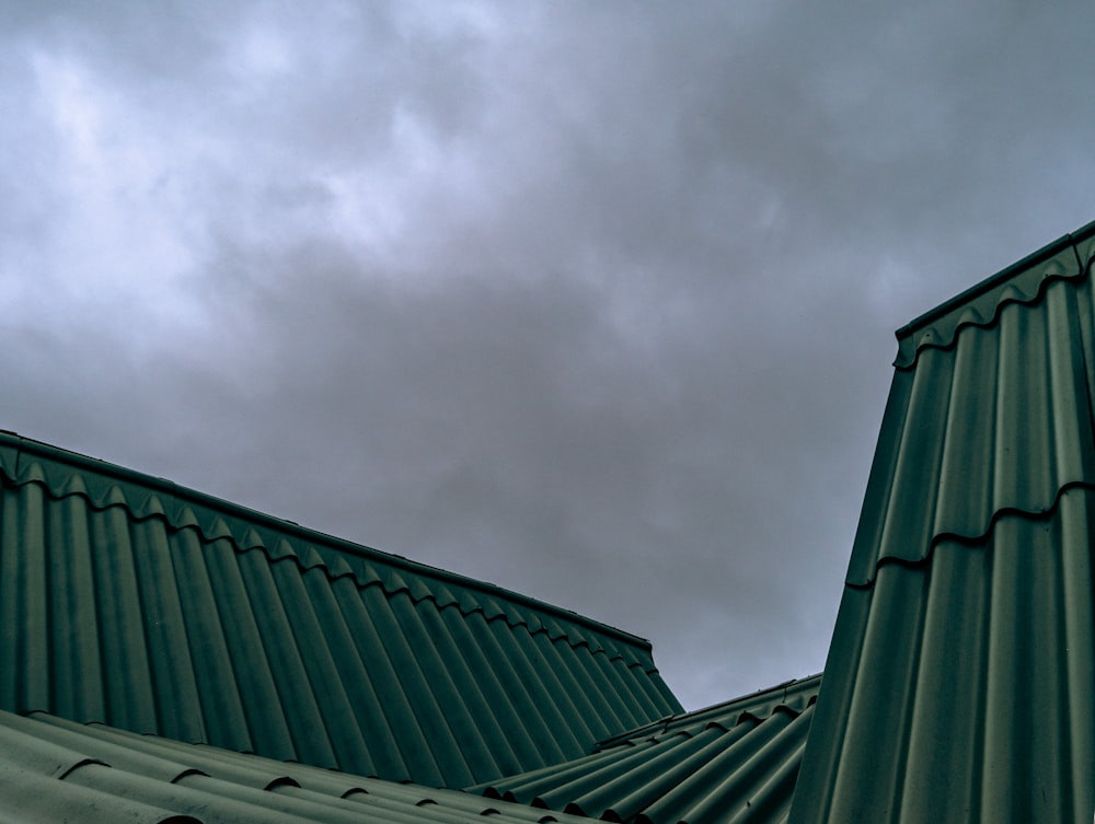 a green metal roof with a cloudy sky in the background