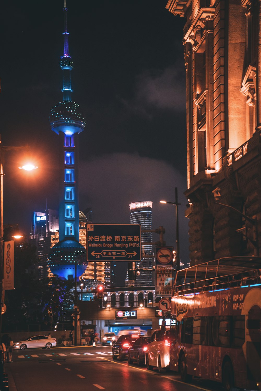 a city street at night with a tall building in the background