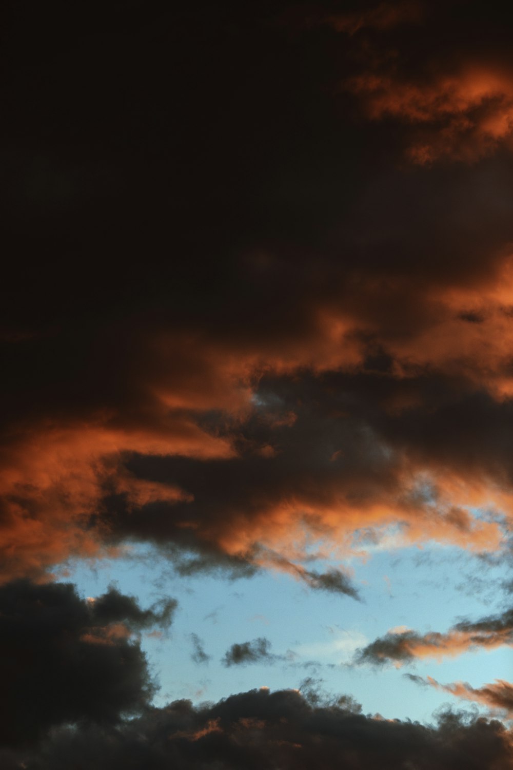 a plane flying through a cloudy sky at sunset