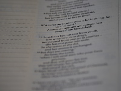 A close-up view of a printed page with text in English. The text appears to be from a religious scripture, specifically verses or passages, with some words in bold.