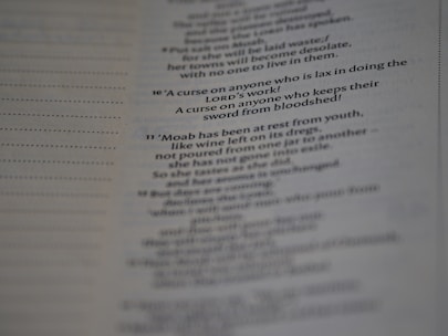 A close-up view of a printed page with text in English. The text appears to be from a religious scripture, specifically verses or passages, with some words in bold.