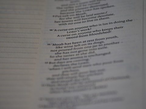 A close-up view of a printed page with text in English. The text appears to be from a religious scripture, specifically verses or passages, with some words in bold.