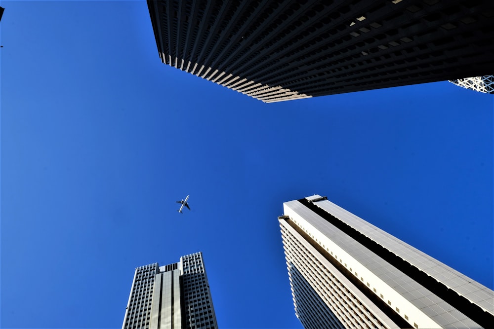 an airplane flying in the sky between two tall buildings
