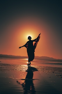 A cinematic frame showing a silhouette of a dancer mid-movement against a glowing sunset