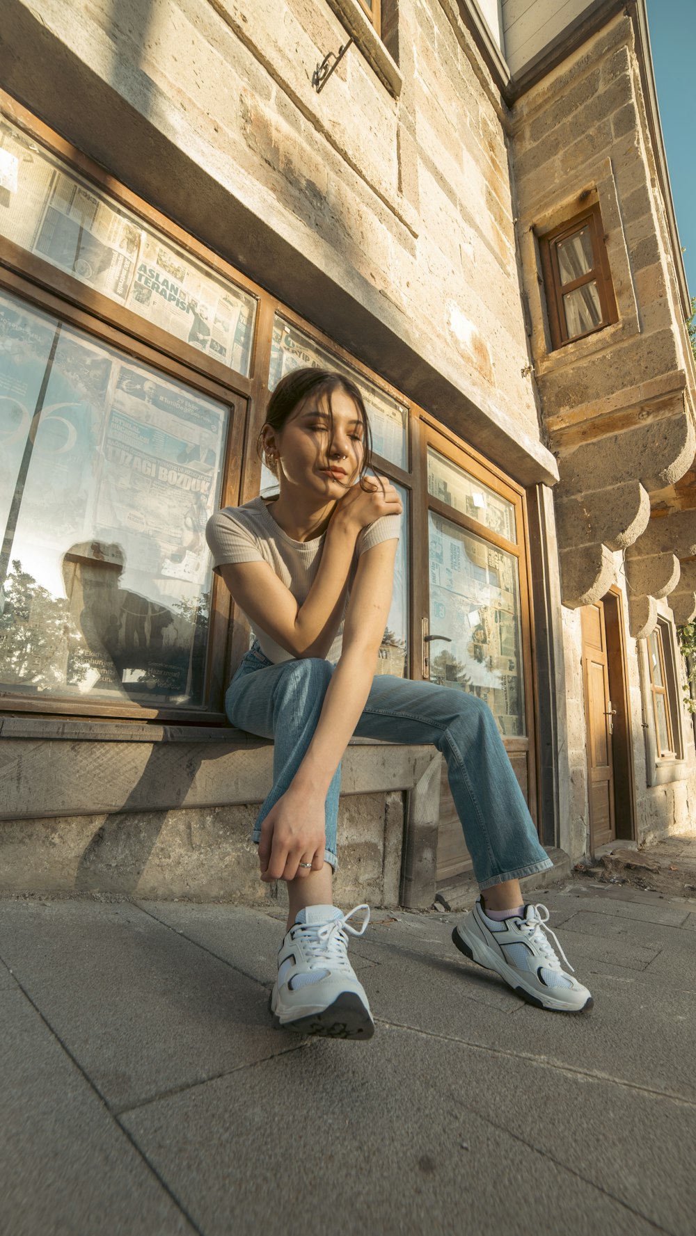 a woman sitting on a window sill in front of a building