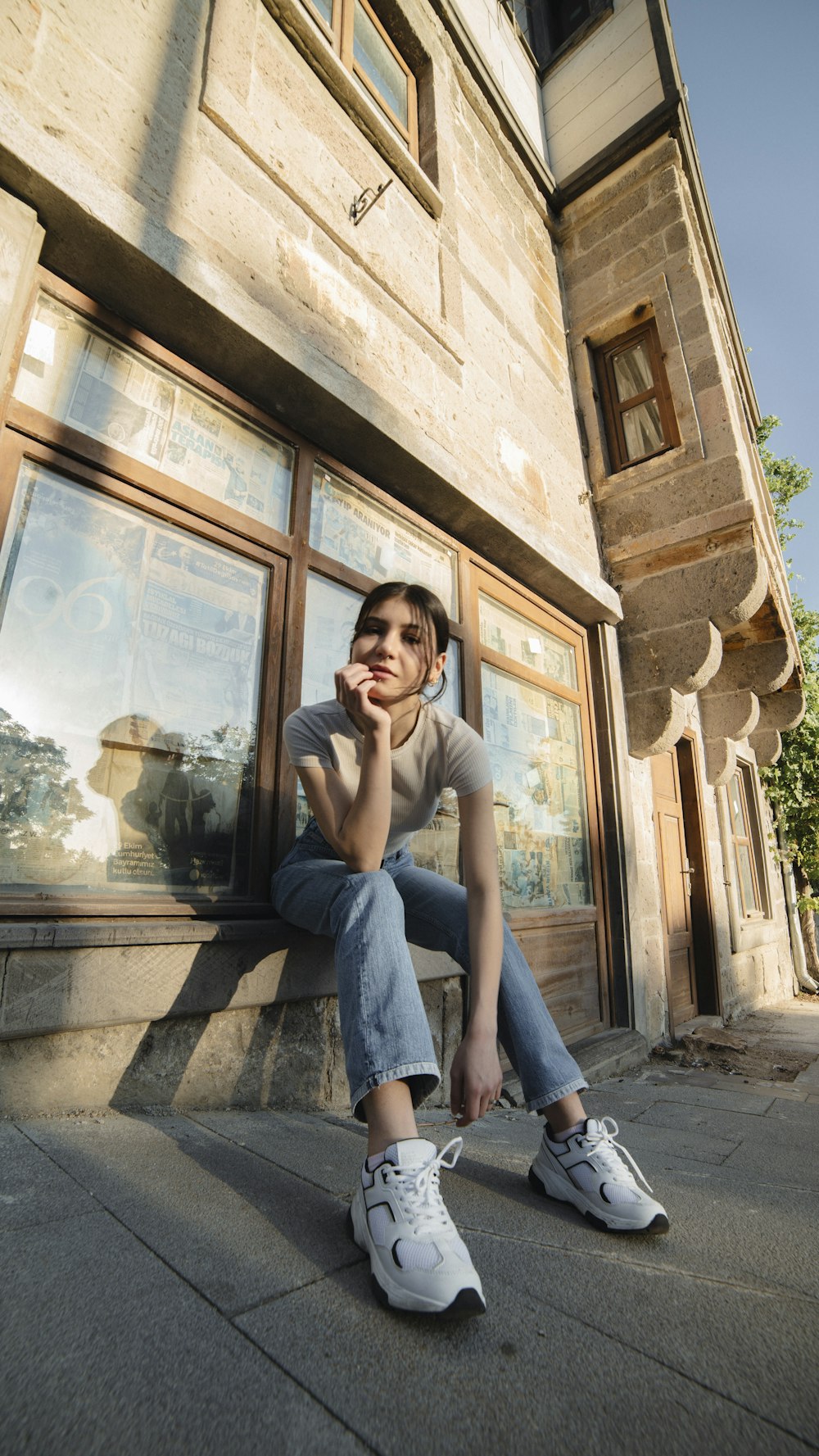 a woman sitting on a ledge in front of a building