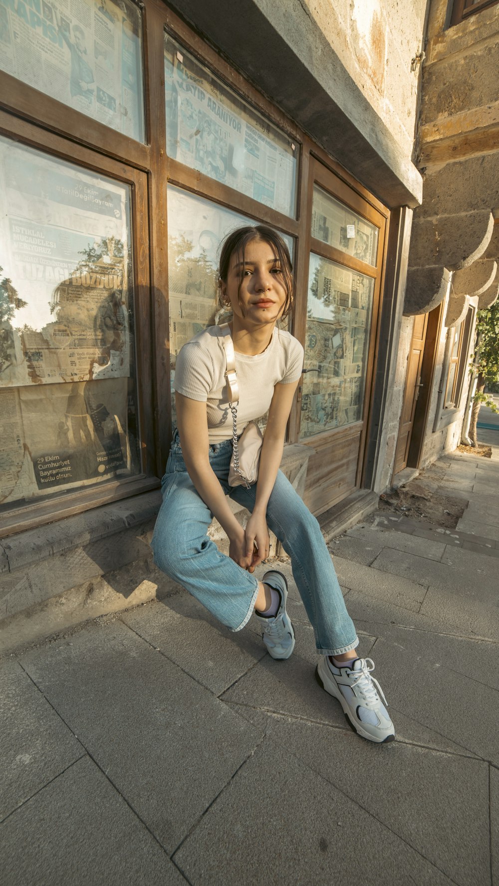 a woman sitting on the sidewalk in front of a store