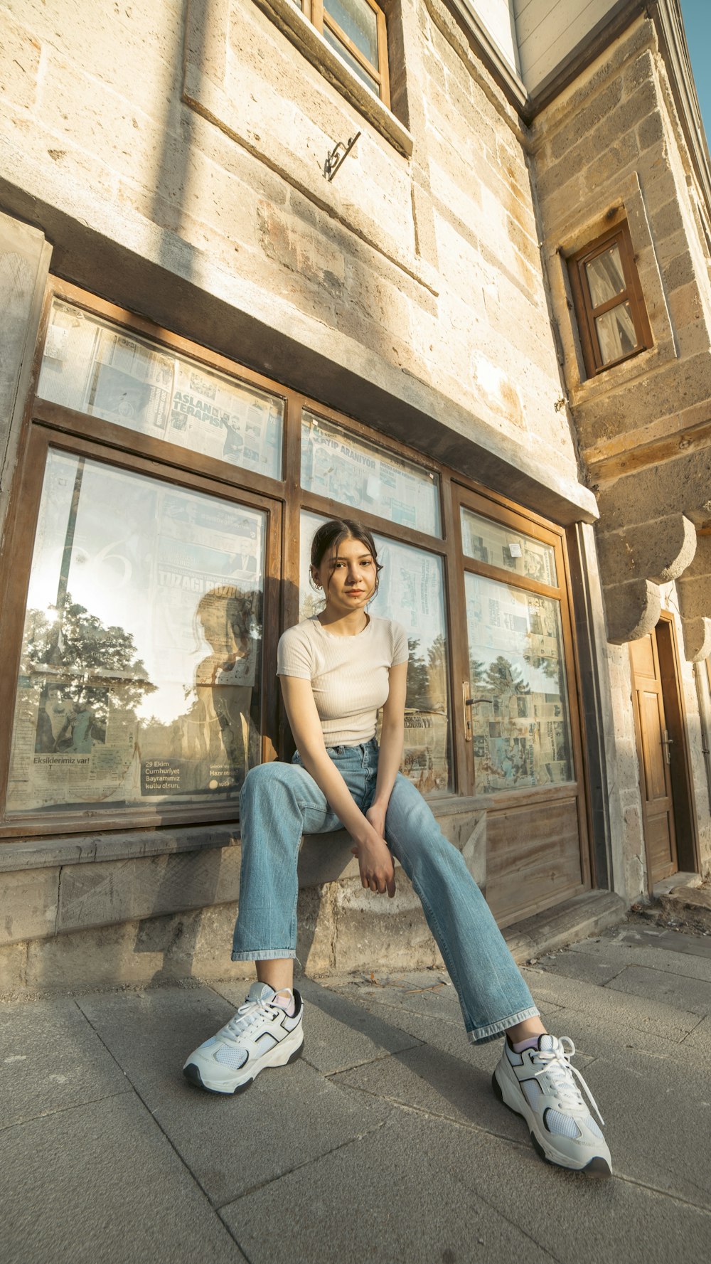 a woman sitting on a ledge in front of a building