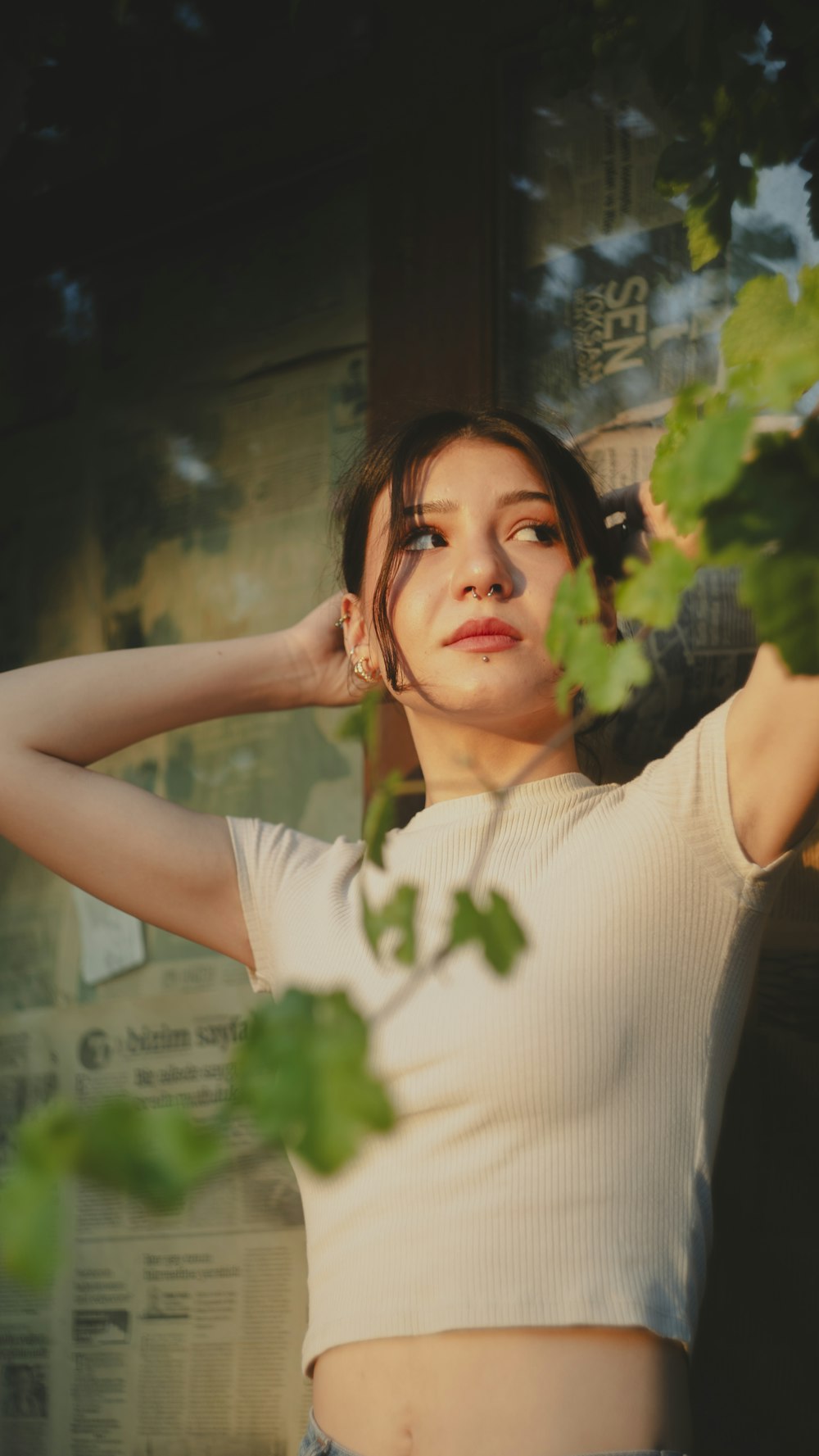 a woman standing next to a tree with her hands on her head