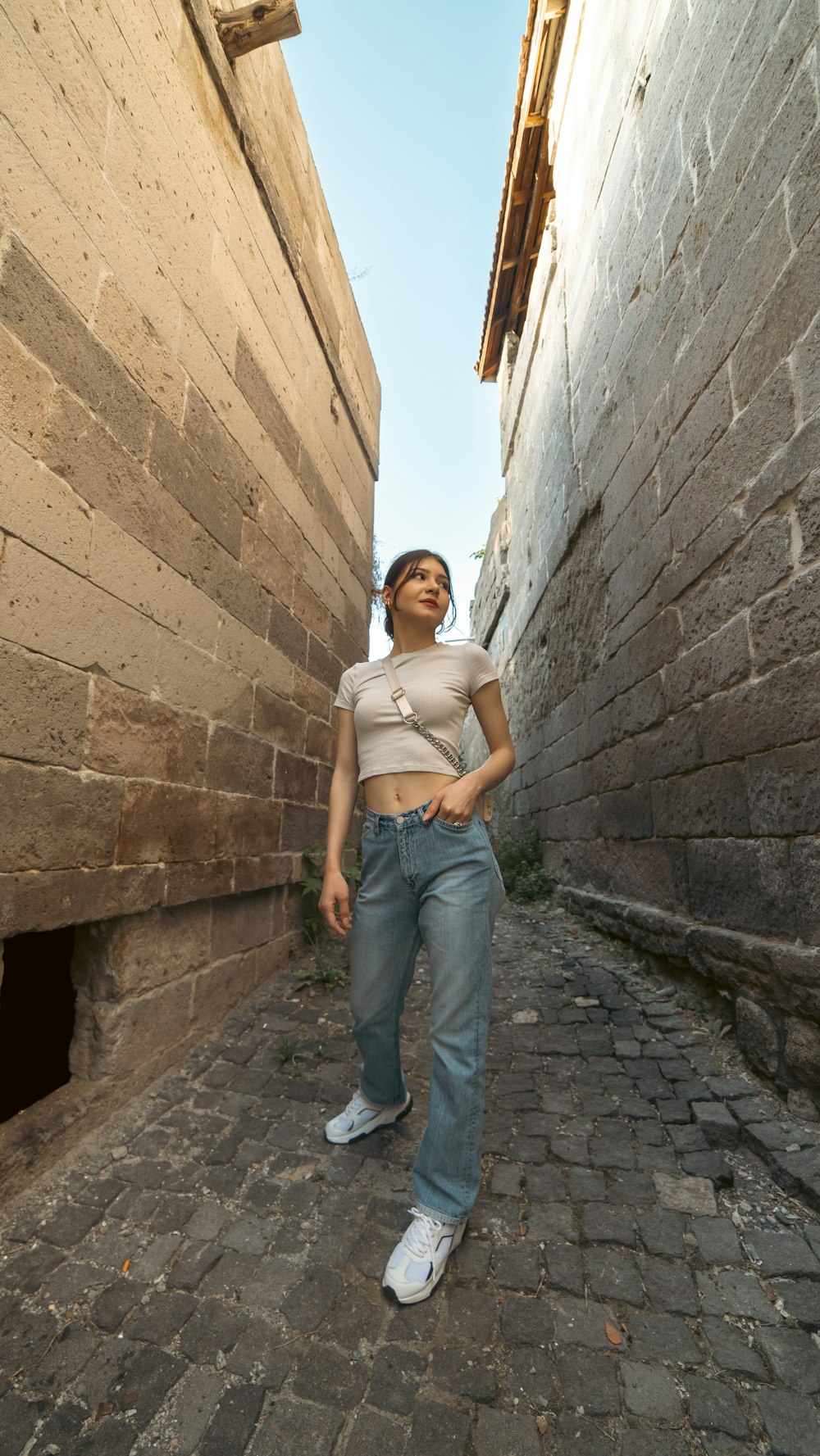 a woman standing in an alley between two buildings