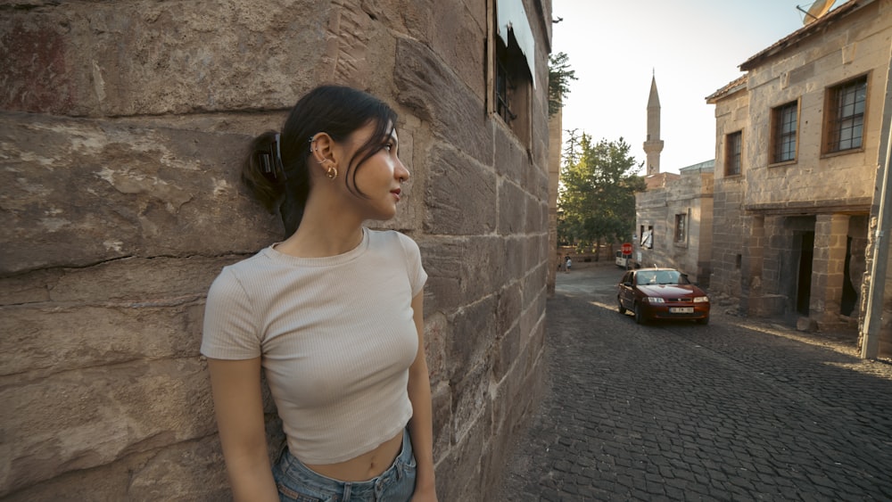 a woman standing next to a stone wall