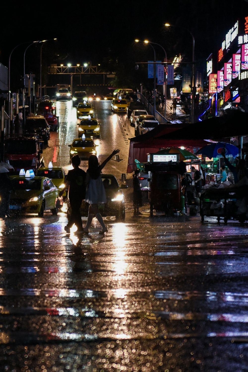 a couple of people crossing a street at night