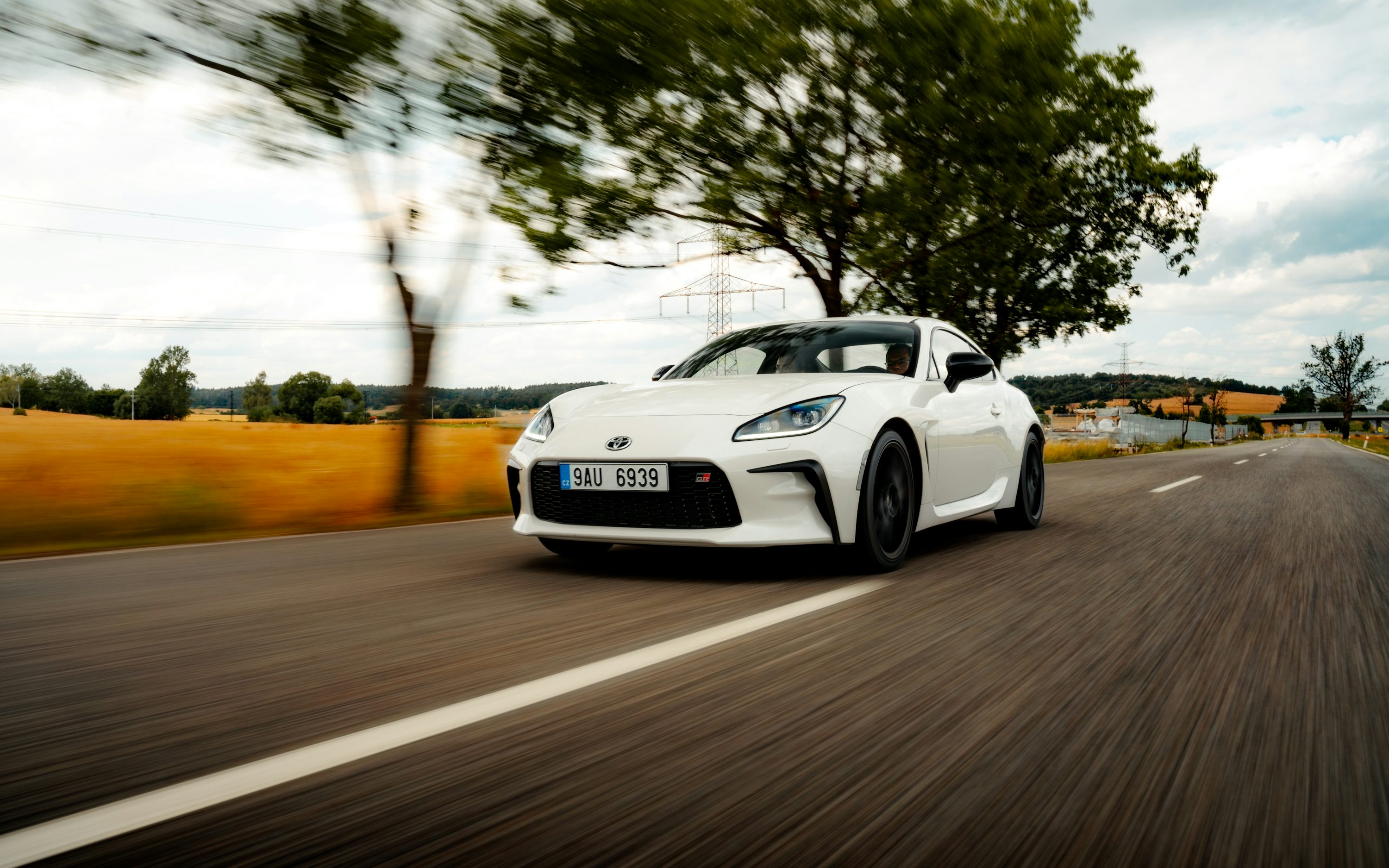 a white sports car driving down the road