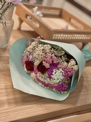 A beautifully arranged bouquet of seasonal flowers resting on a vintage wooden table.