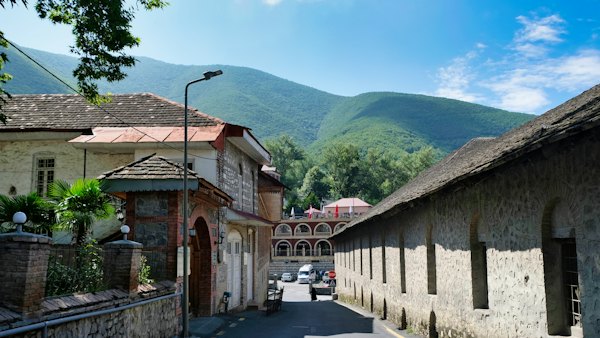 A street lined with stone buildings with mountains in the background — Sheki, Azerbaijan