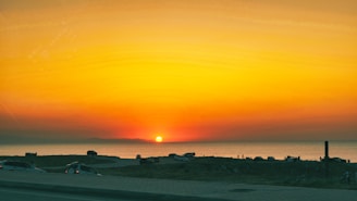 A vibrant sunset over a tropical beach with a rented car parked nearby
