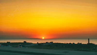 A vibrant sunset over the Visakhapatnam coastline with a rented car parked nearby.