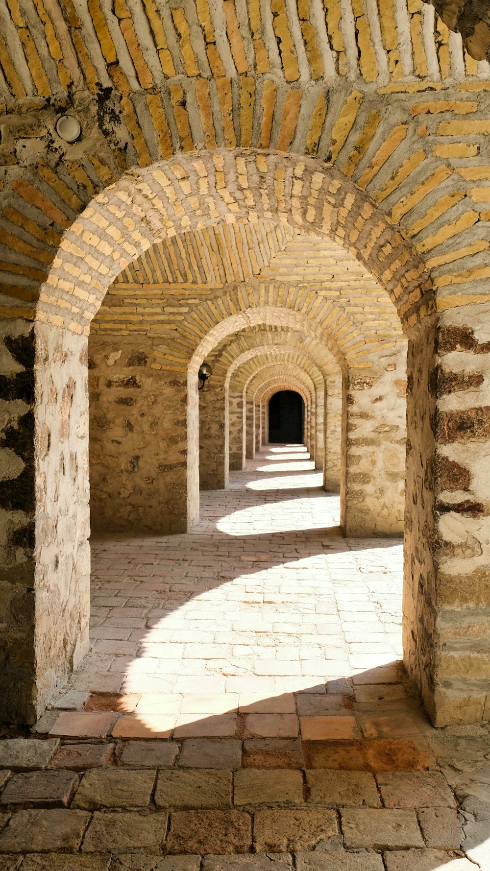 a stone tunnel with a clock on the wall