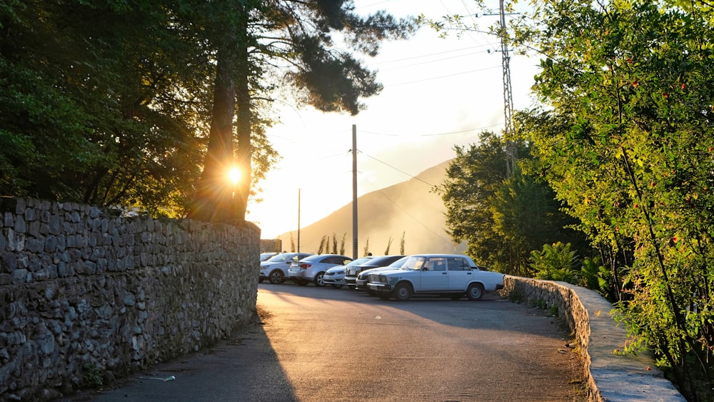 cars parked on the side of a road near a stone wall