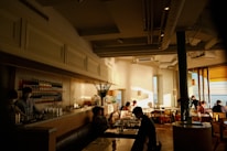 Sunlight streaming through café windows onto cozy seating with customers enjoying their drinks.