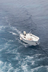 a small white boat in the middle of the ocean