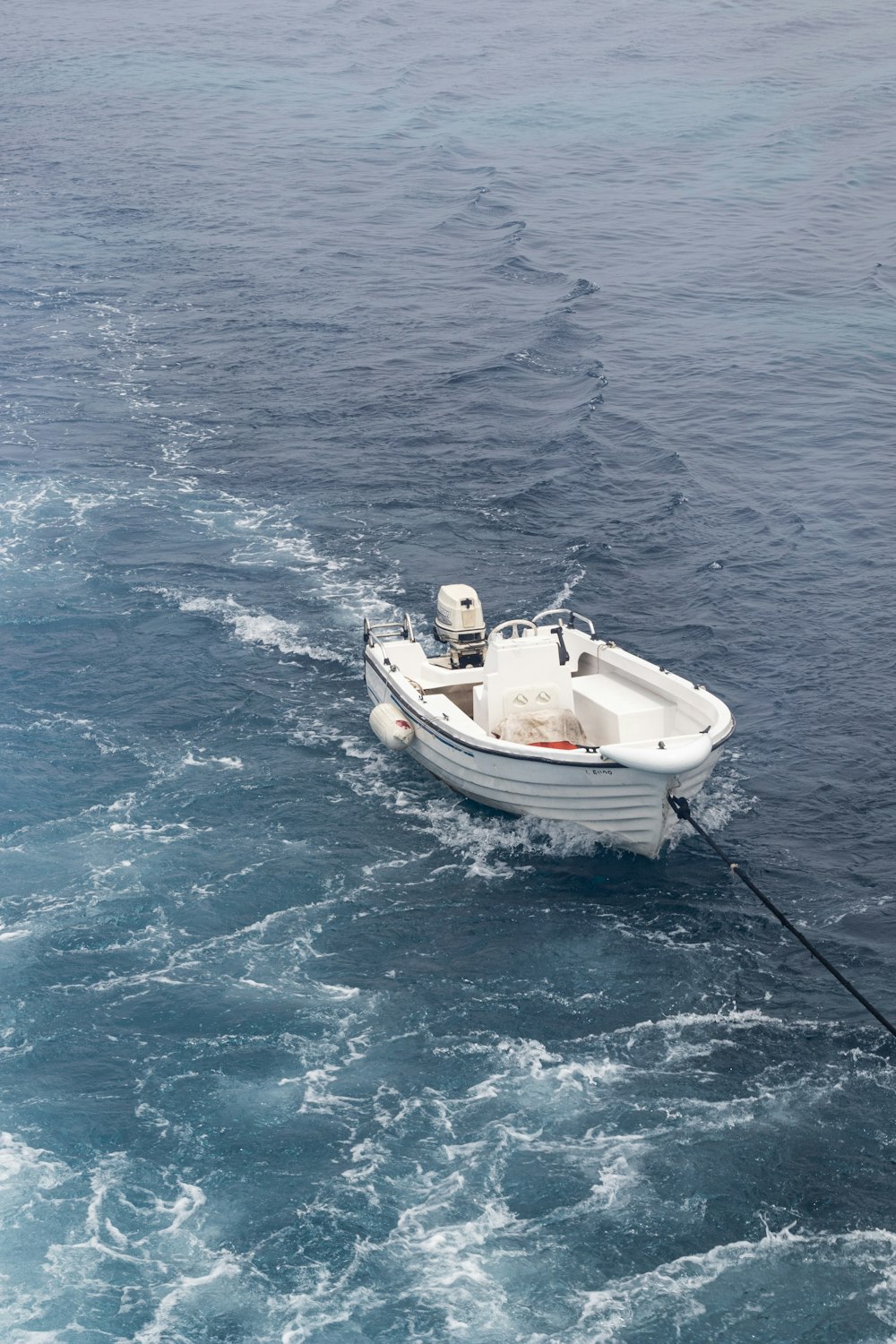 a small white boat in the middle of the ocean