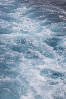 Hyper-realistic ocean wave resin painting showing turquoise and deep blue waves with white foam cells, glossy and fluid texture on aluminum substrate.